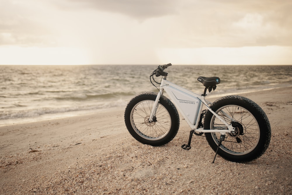 a bicycle parked on a beach near the ocean