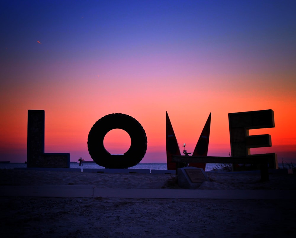 a large love sign sitting on top of a sandy beach