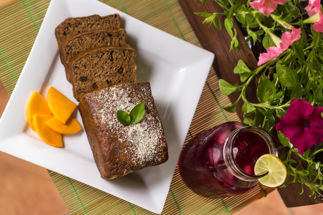 a white plate topped with slices of cake next to a glass of juice, Jamaican Easter Bun and cheese with a cool drink