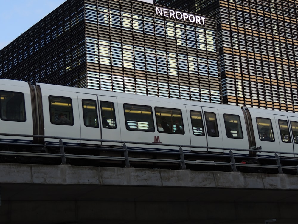 a white train traveling past a tall building