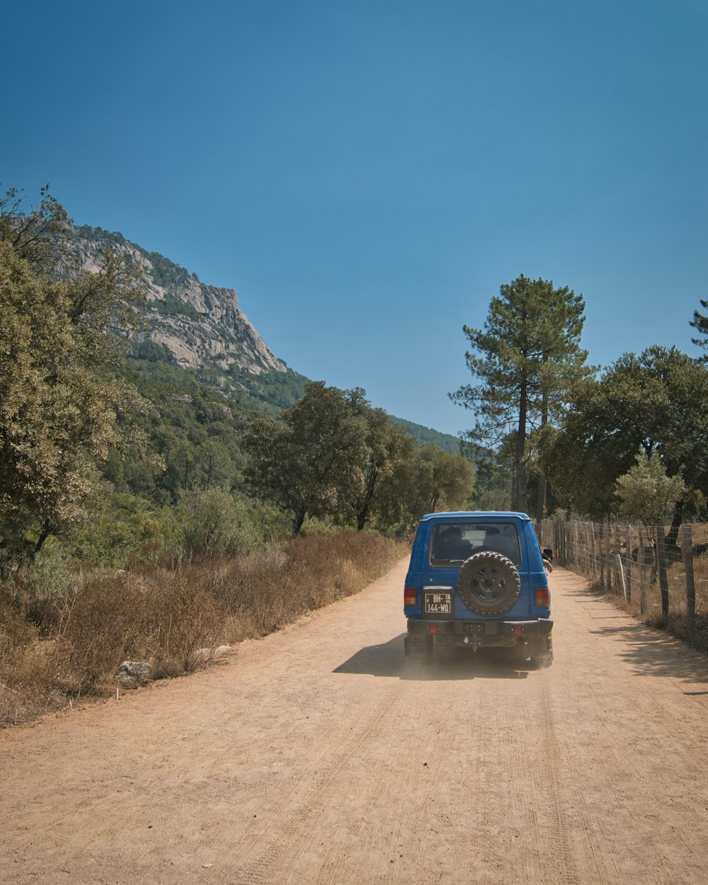 a blue van driving down a dirt road