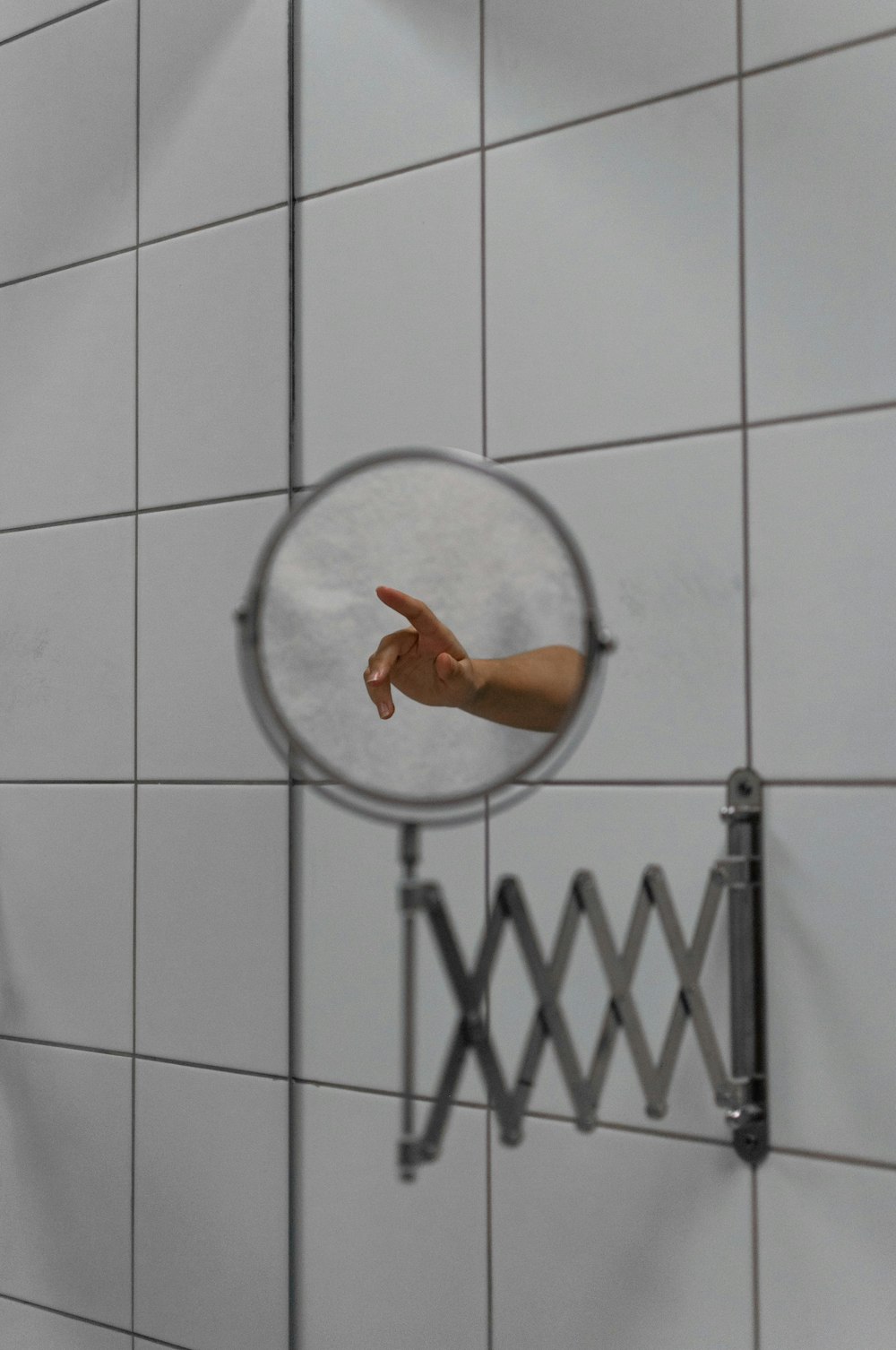 a hand pointing at a mirror in a bathroom