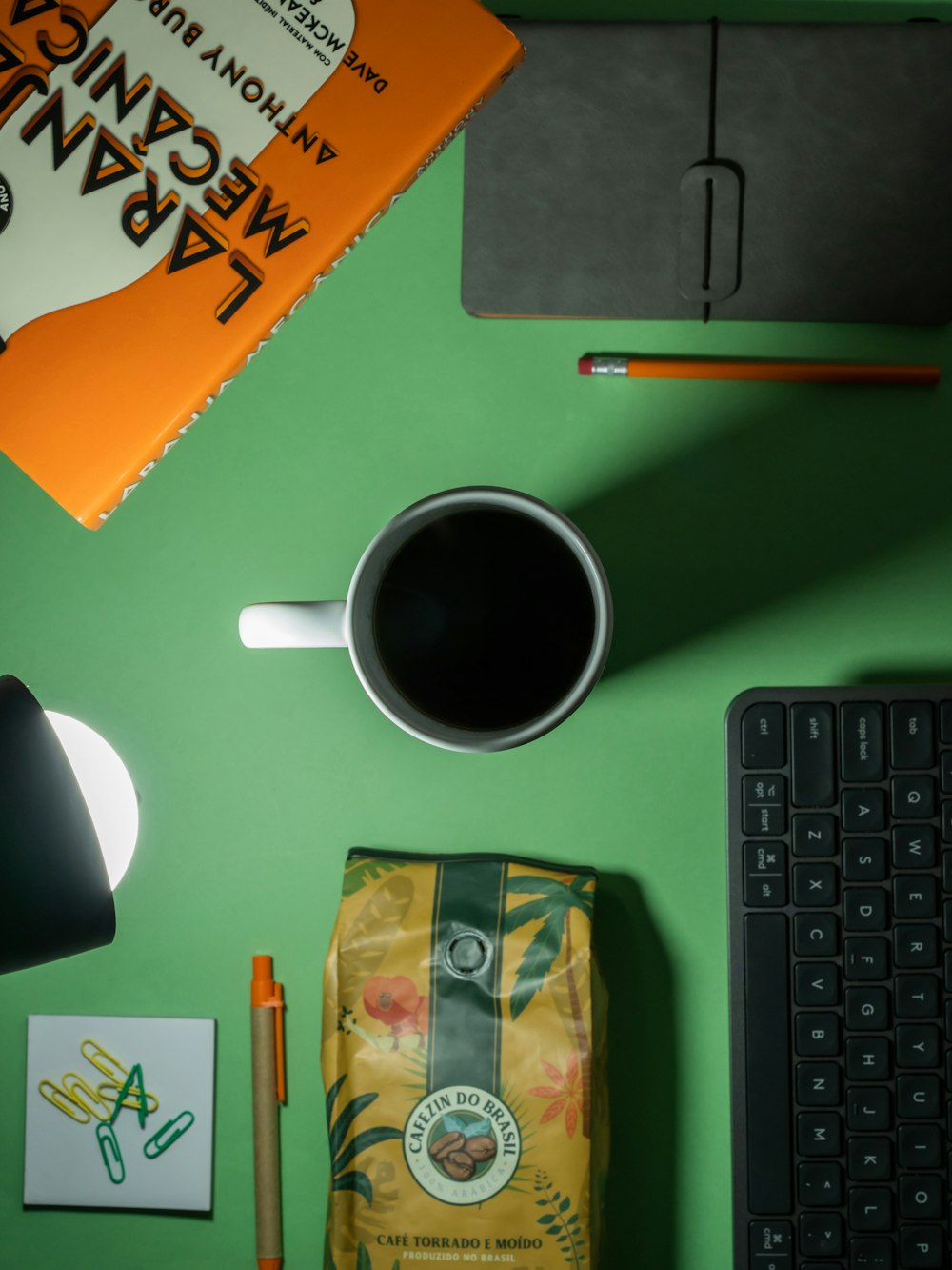 a green desk with a keyboard, mouse and coffee