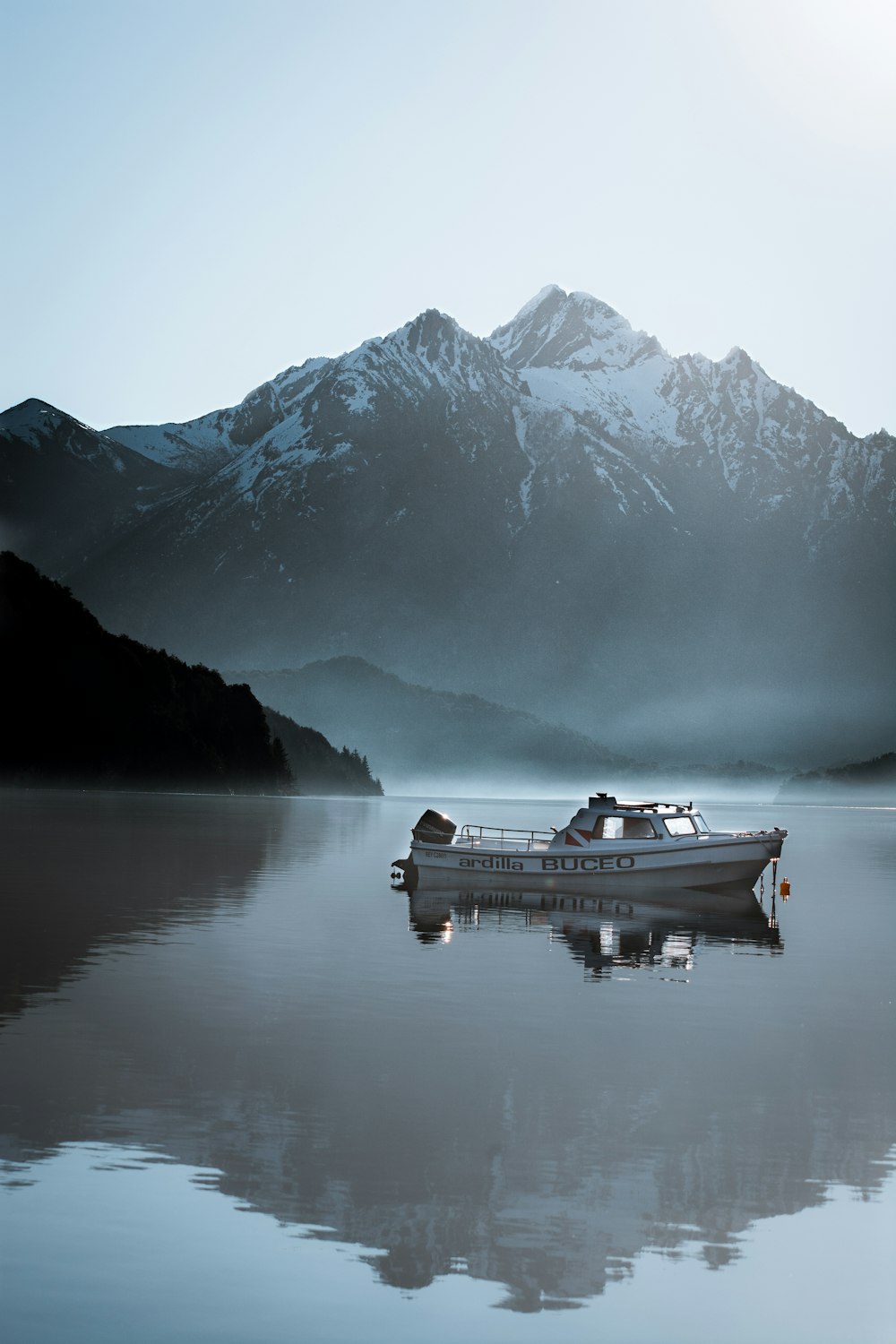 Un barco flotando en la cima de un lago junto a una montaña