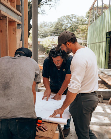 a group of men standing around a white sheet of paper