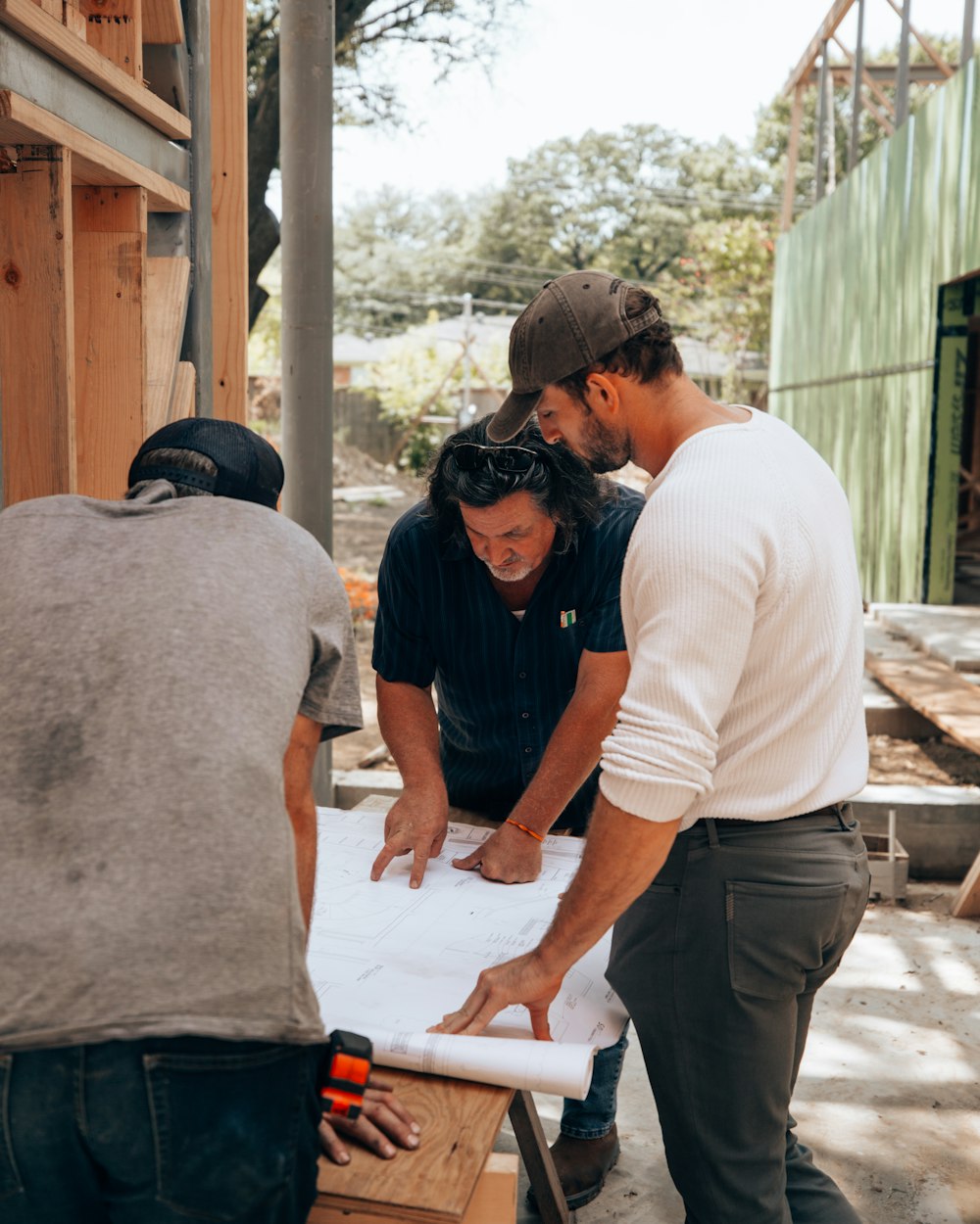 a group of men standing around a white sheet of paper