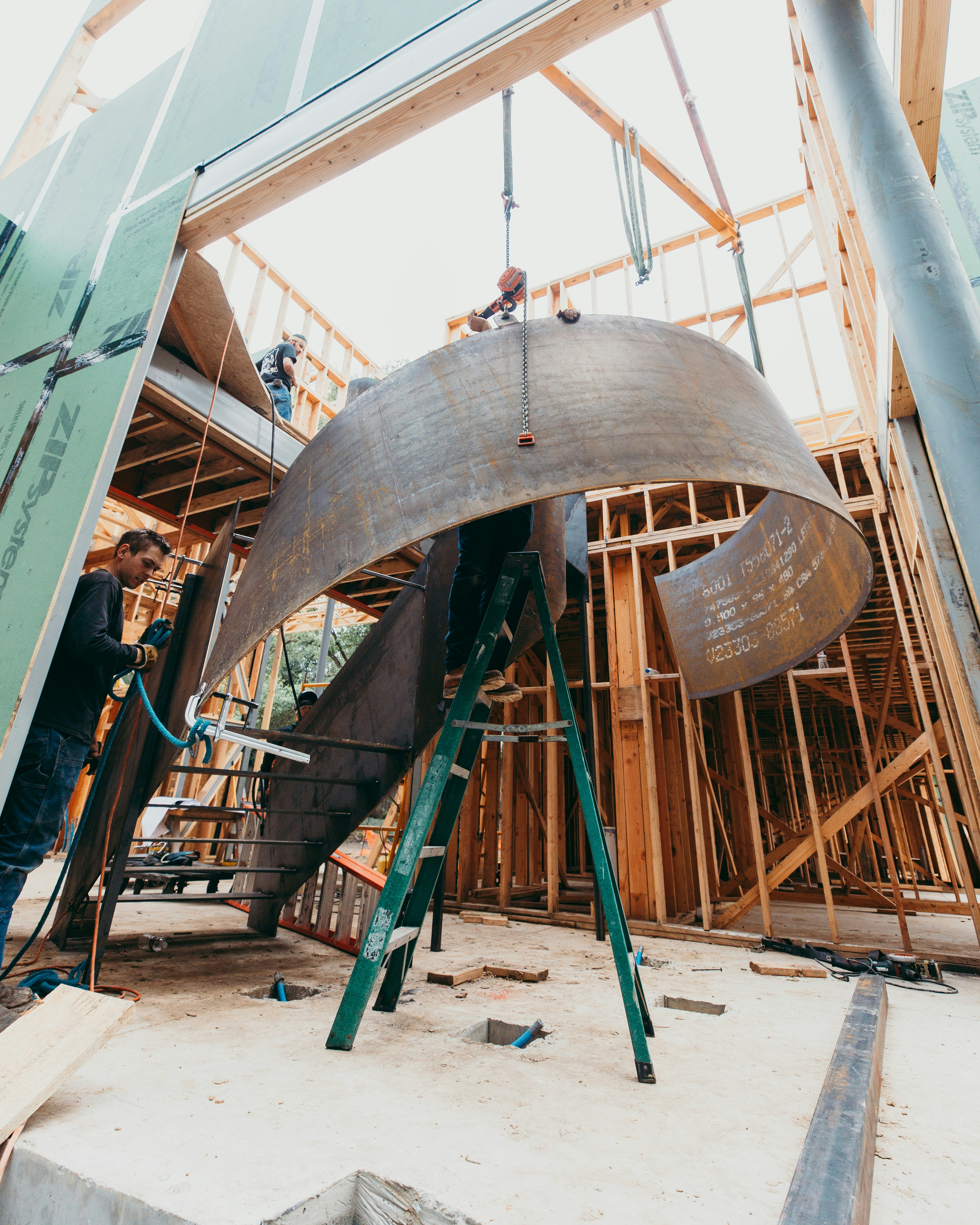 Workers install a curved metal structure inside a building.