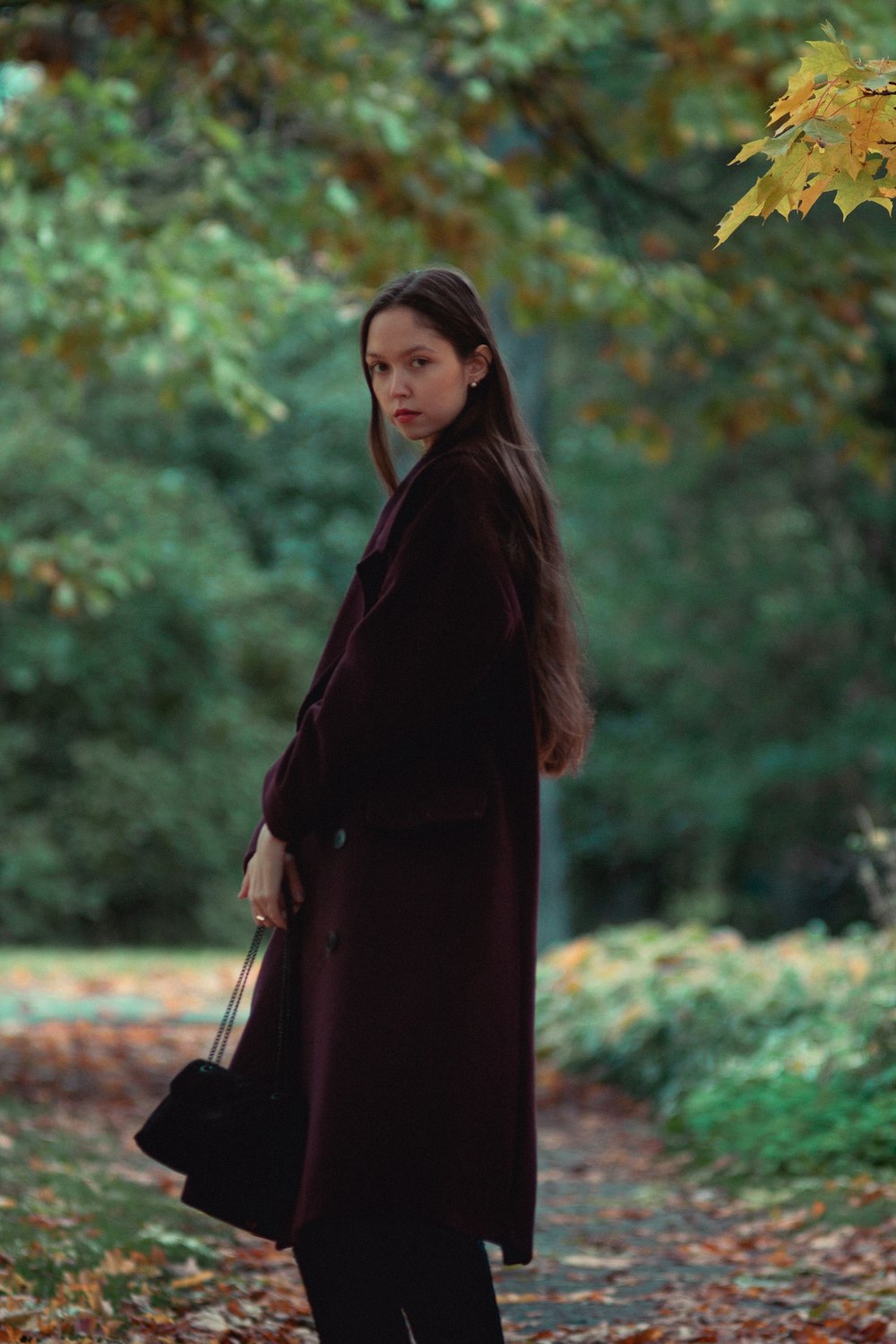 a woman standing on a leaf covered path