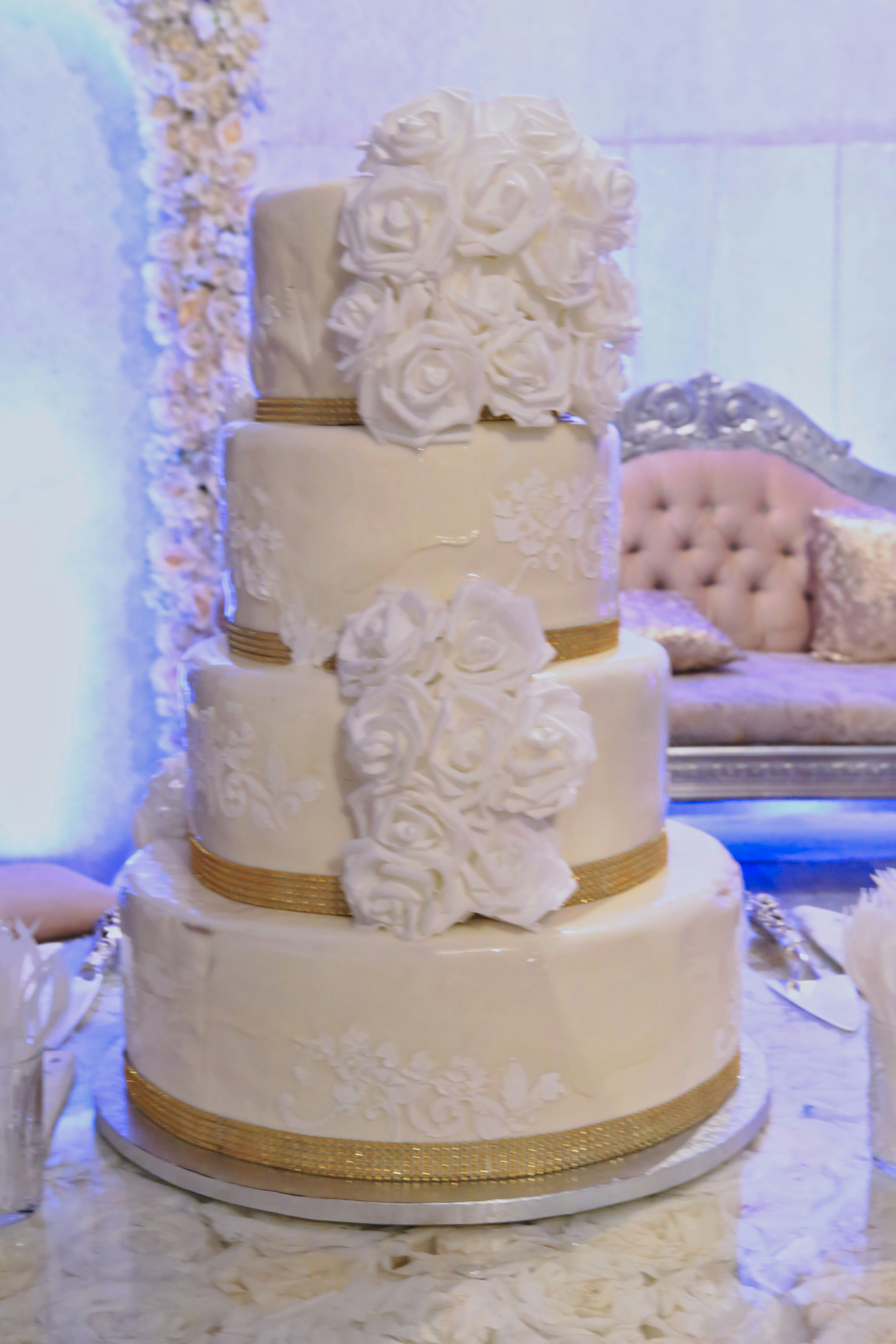 Elegant white and gold two-tier cake with hand-painted floral motifs and gold ribbon