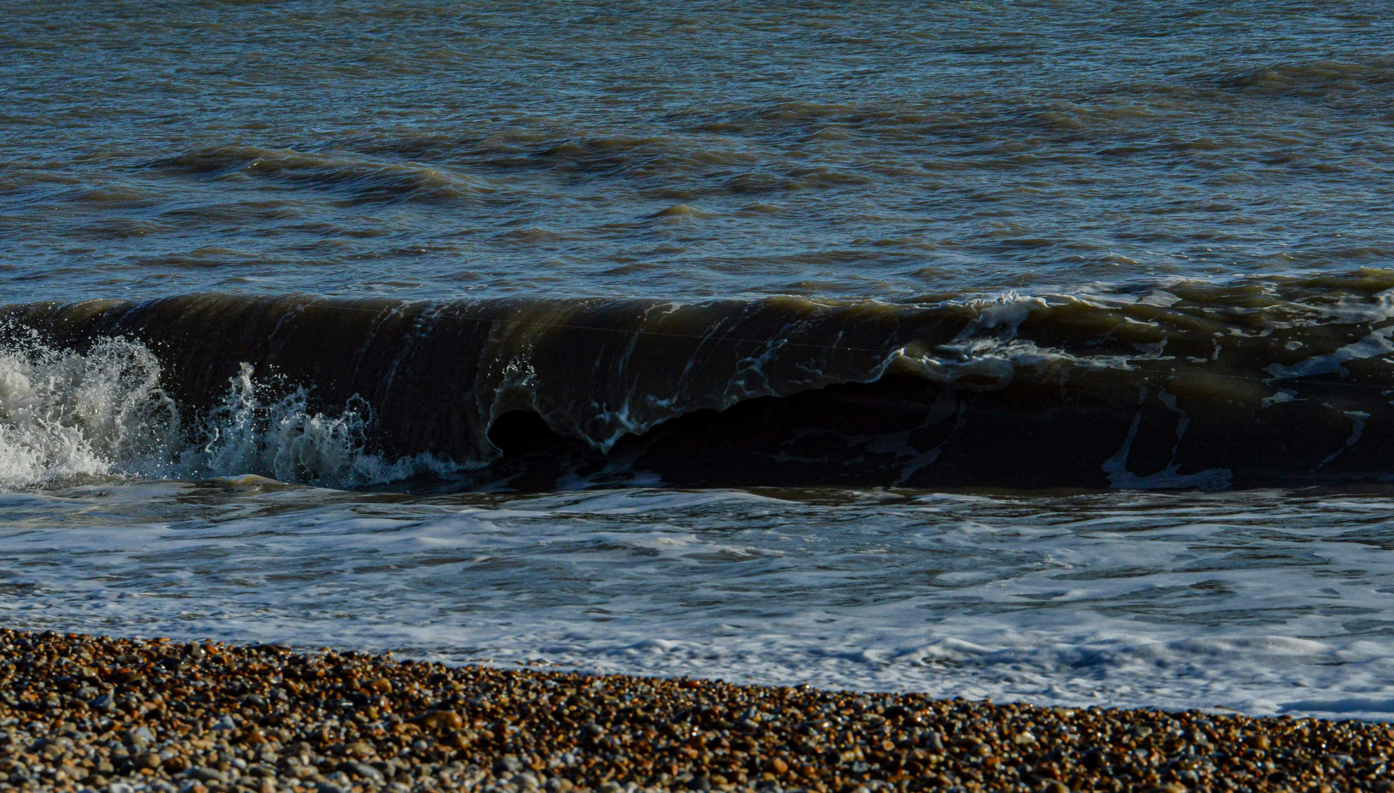 a wave rolls in on the shore of a beach