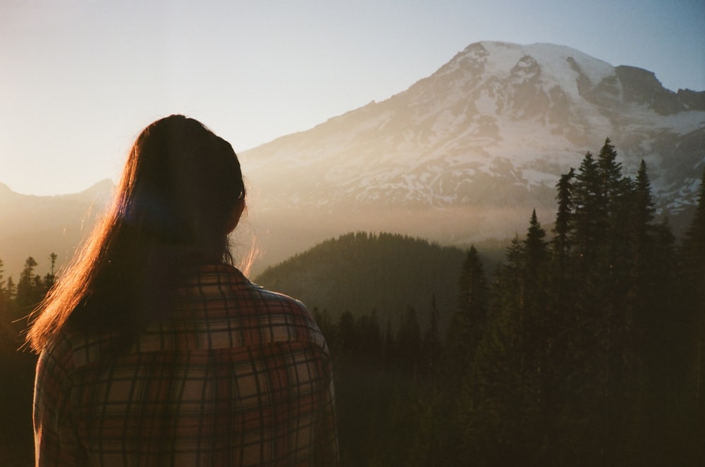a woman standing in front of a mountain at sunset