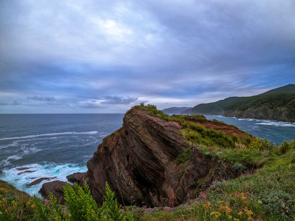 a rocky cliff overlooks the ocean on a cloudy day