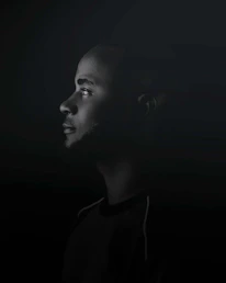 Shadowed profile of a focused negotiator analyzing non-verbal cues in a dimly lit conference room.