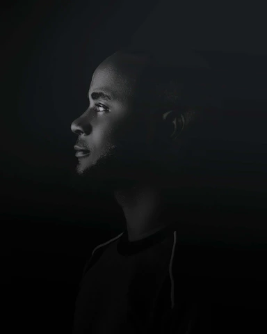 Shadowed profile of a focused negotiator analyzing non-verbal cues in a dimly lit conference room.