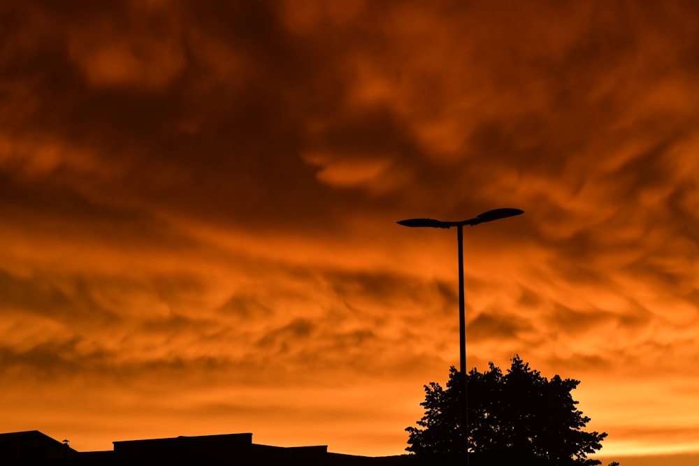 a street light in front of an orange sky