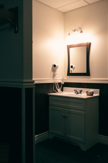 A bathroom shelf displaying a hair dryer, electric toothbrush, and hair trimmer arranged neatly with soft lighting.