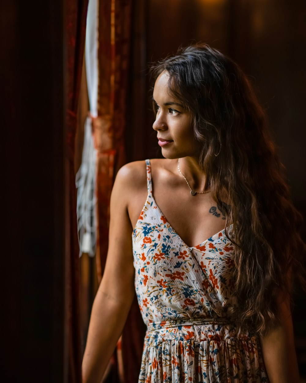 a woman in a floral dress looking out a window