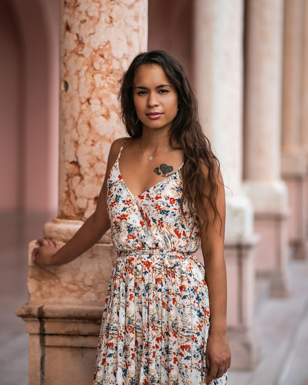 a woman standing next to a pillar wearing a dress