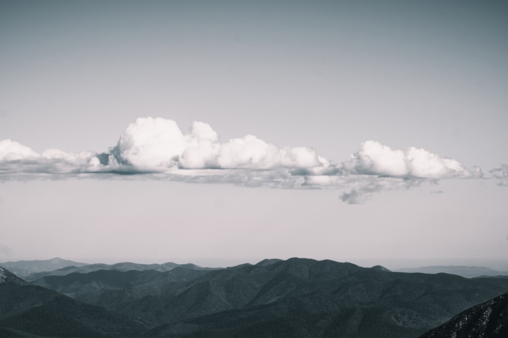 a black and white photo of clouds over mountains