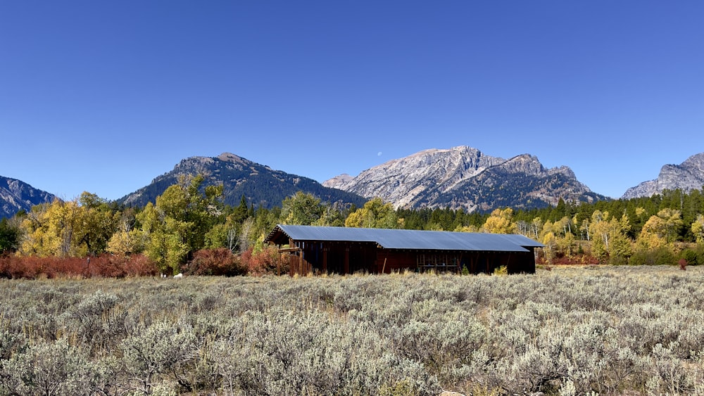 a barn in a field with mountains in the background