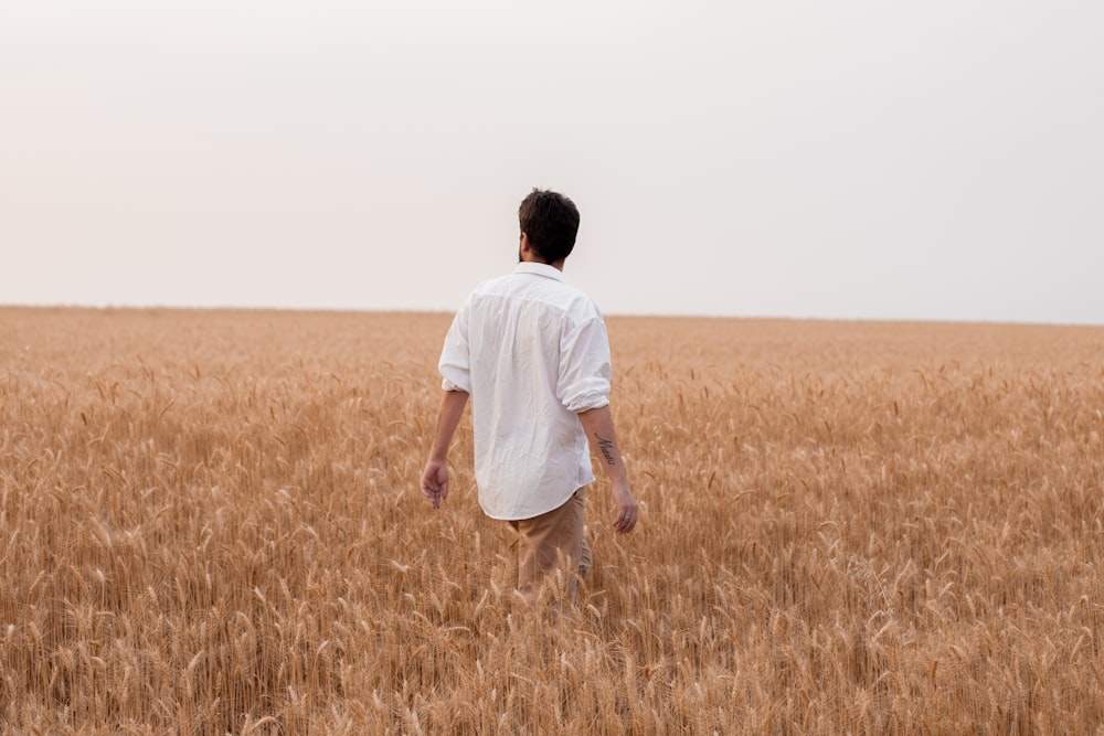 a man walking through a field of wheat