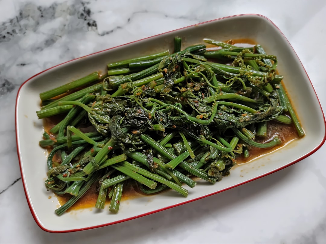 a white plate topped with green beans and broccoli, Tumis Daun Pucuk Labu