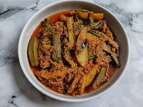 A colorful bowl of spicy Creole gumbo garnished with fresh herbs and a side of crusty bread.