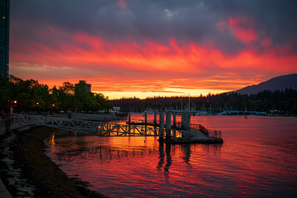 un coucher de soleil sur un plan d’eau avec un quai au premier plan