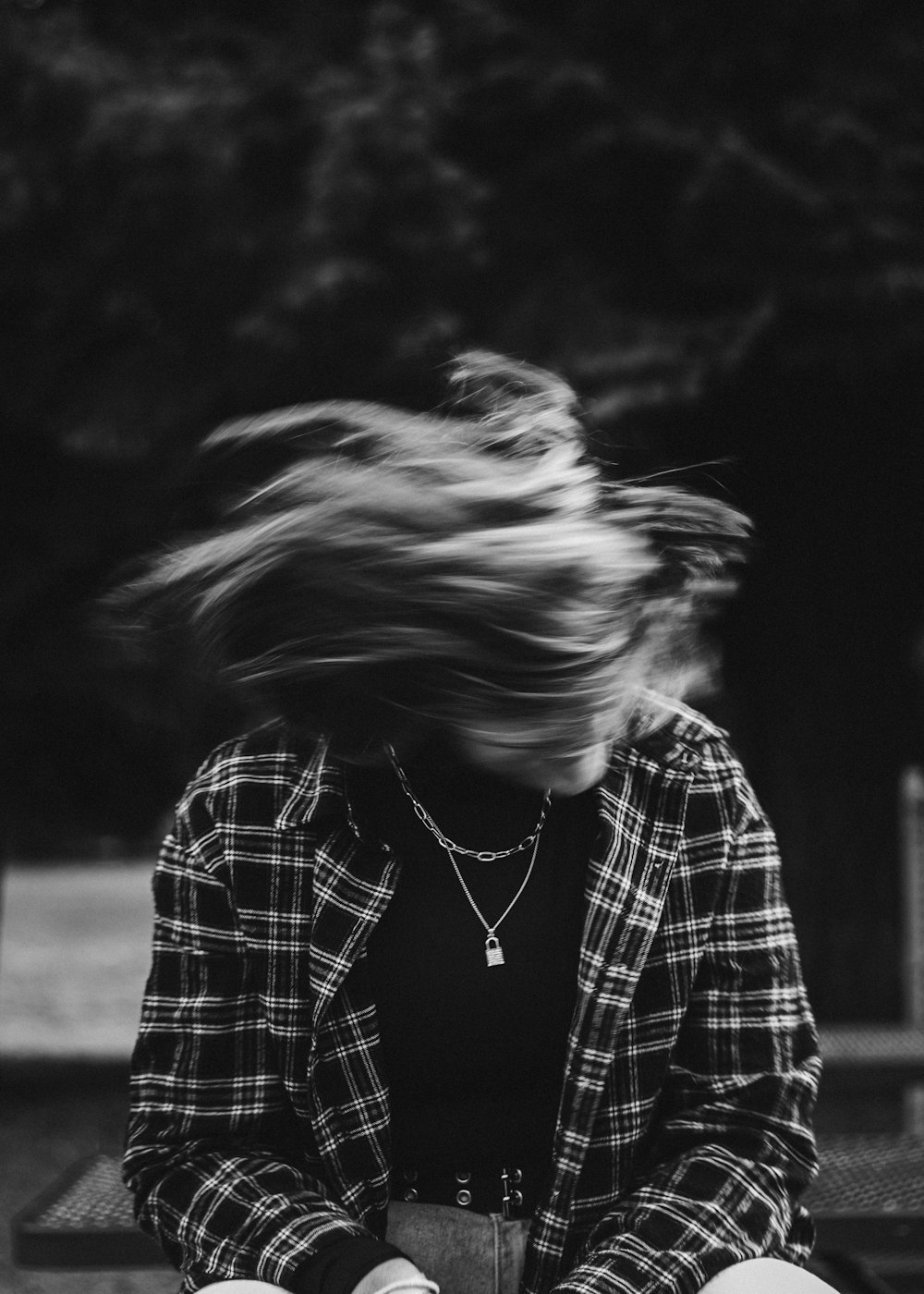 a woman sitting on a bench with her hair in the wind