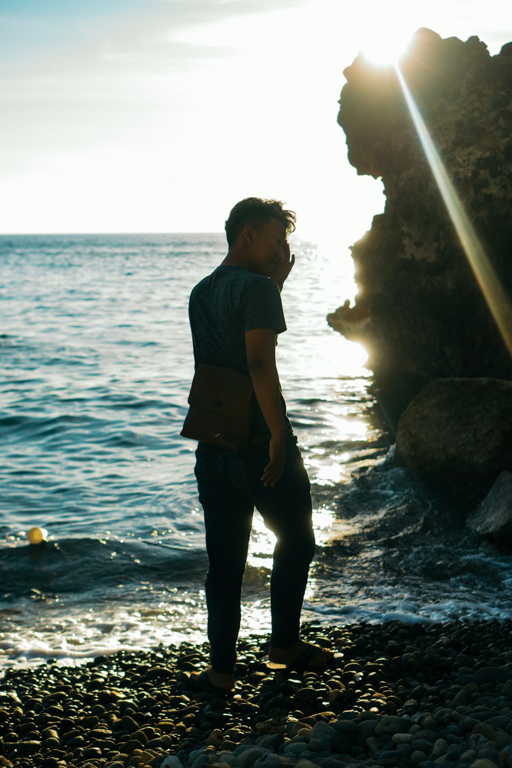 a man standing on a rocky beach next to the ocean