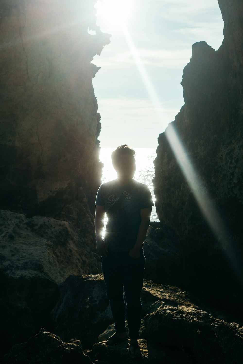 a person standing in a cave looking out at the ocean