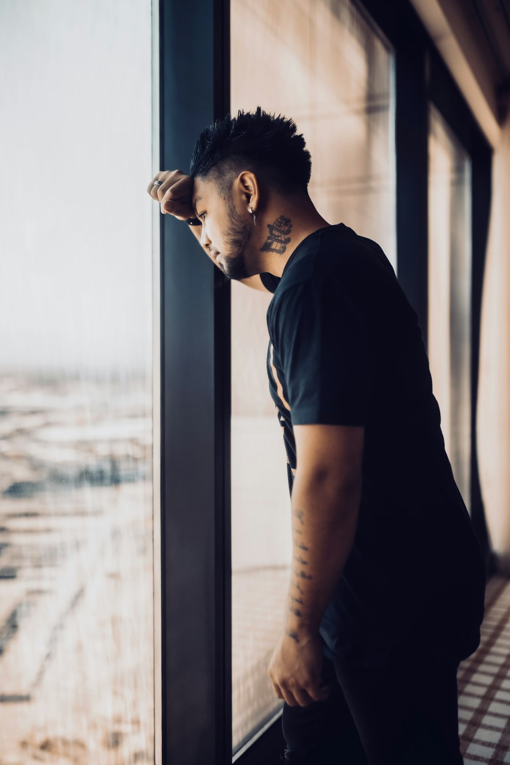 a man looking out a window at the ocean