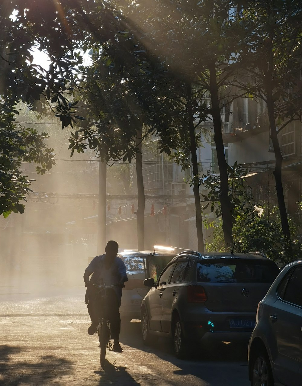 a man riding a bike down a street next to parked cars