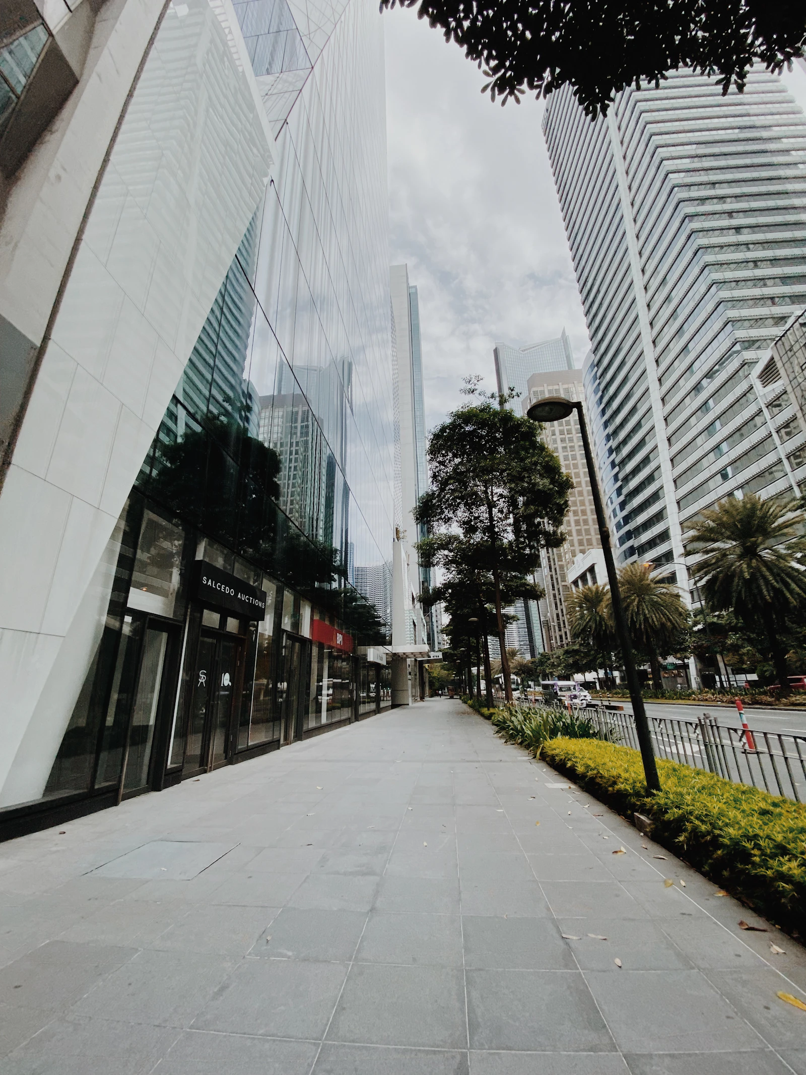 A tree-lined street in Makati with high-rise towers in the background
