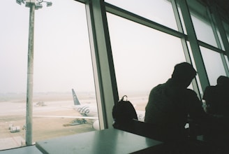 a man looking out a window at an airport