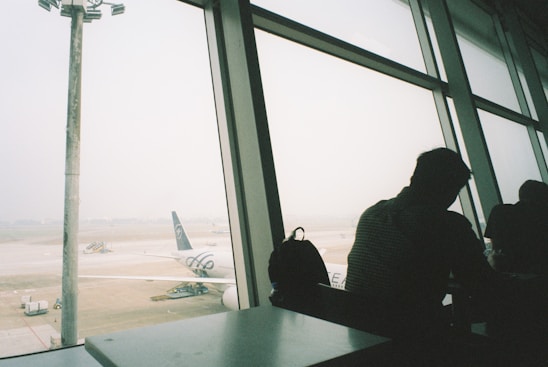 a man looking out a window at an airport