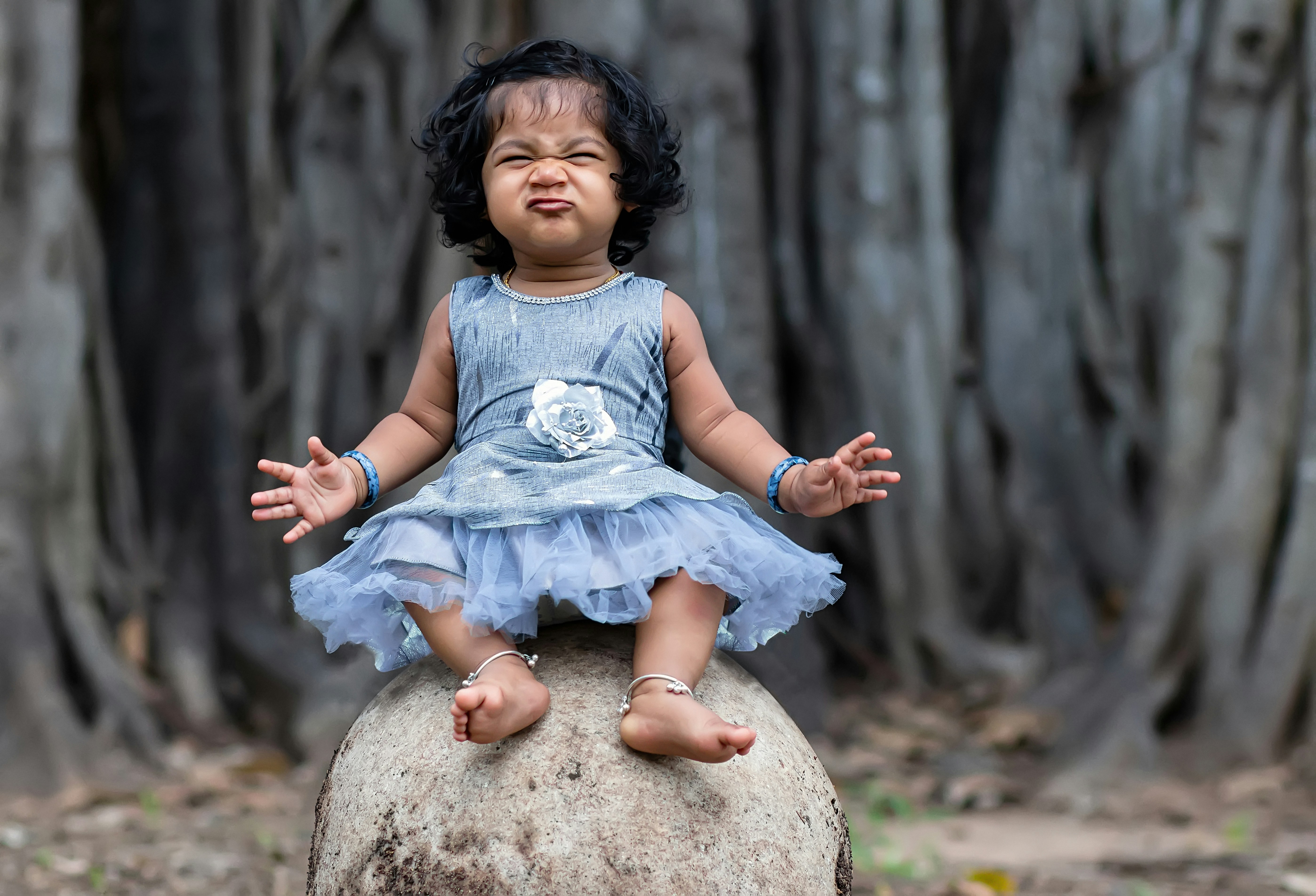 a little girl sitting on top of a rock