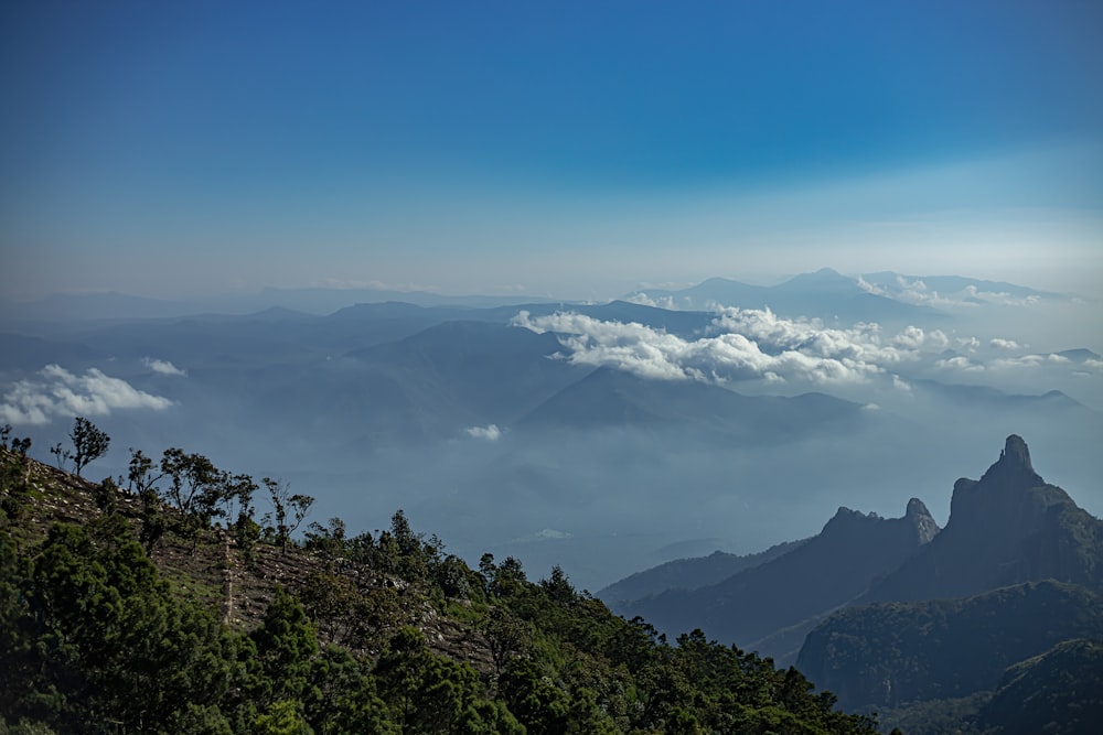 a view of the mountains and clouds from the top of a hill