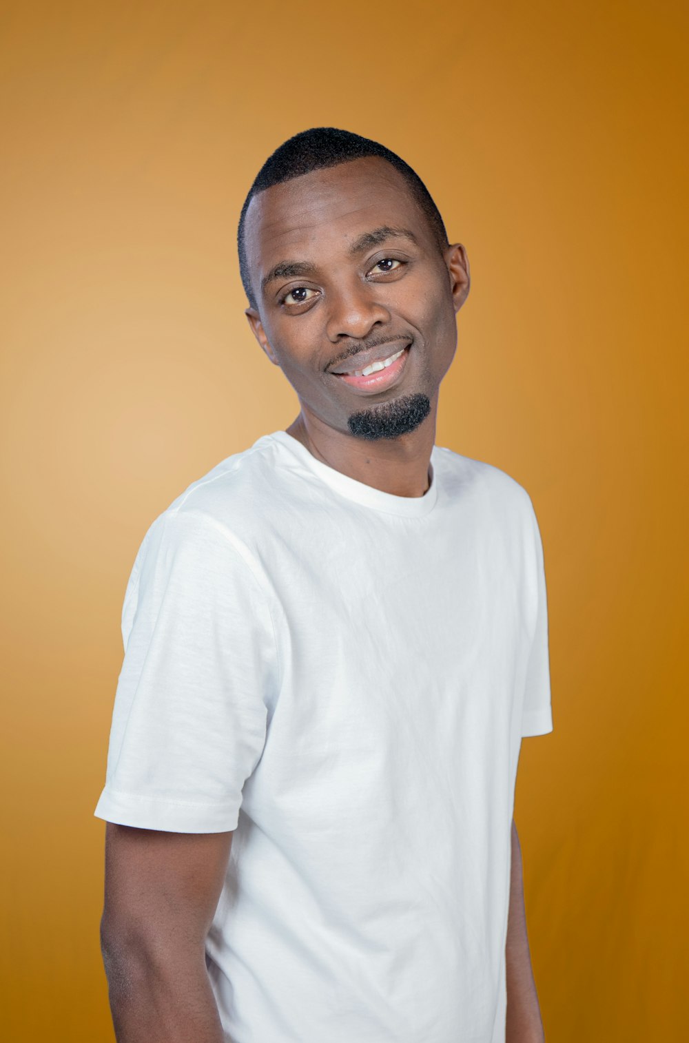 a man in a white t - shirt smiles at the camera