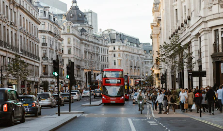 a red double decker bus driving down a busy street