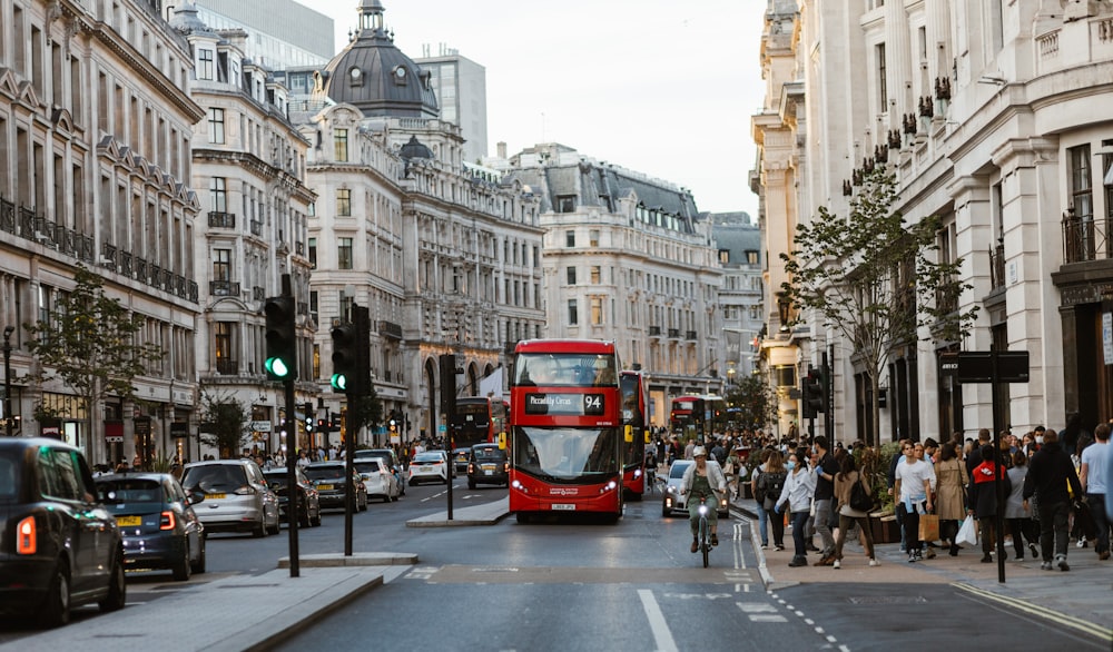 a red double decker bus driving down a busy street