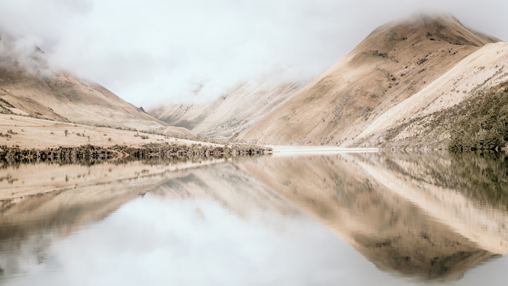 a body of water surrounded by mountains and clouds