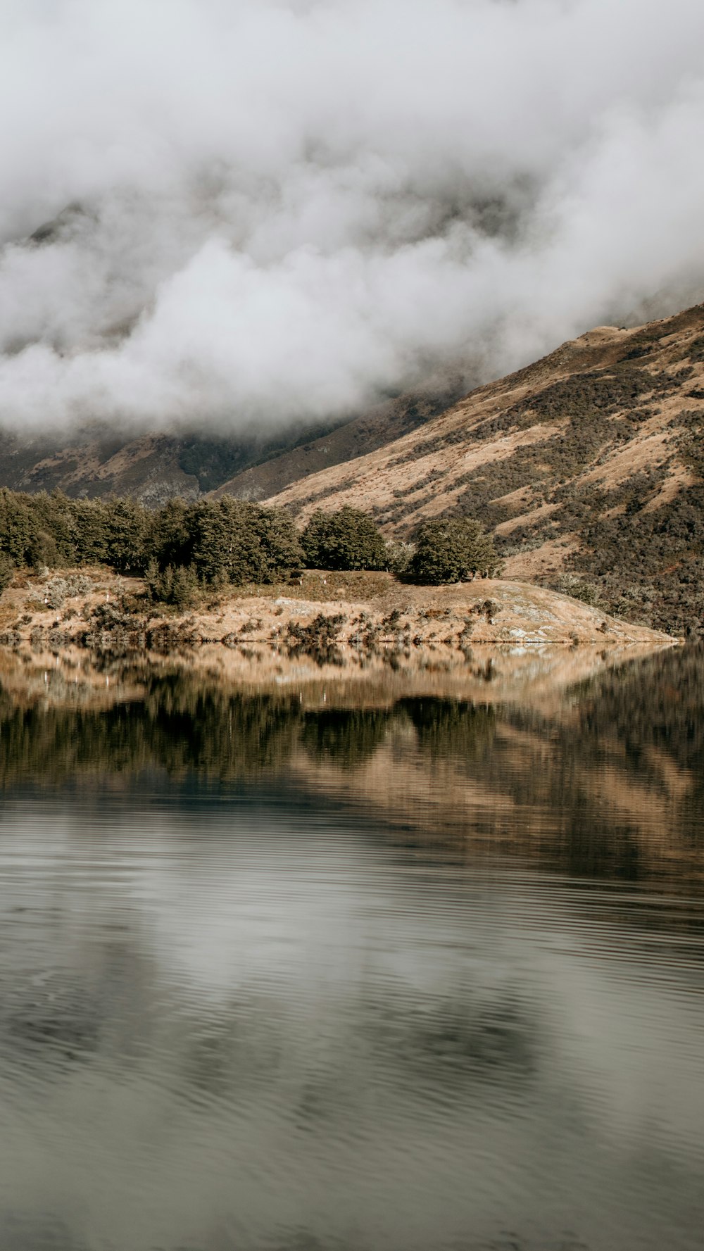 a body of water surrounded by mountains and clouds