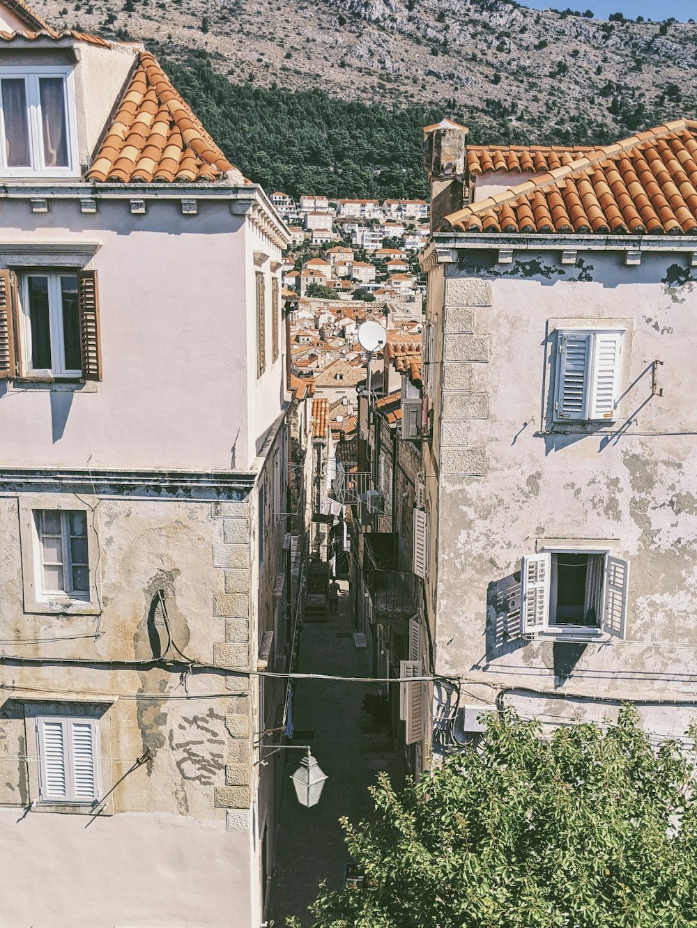 a narrow alley way with buildings and a mountain in the background