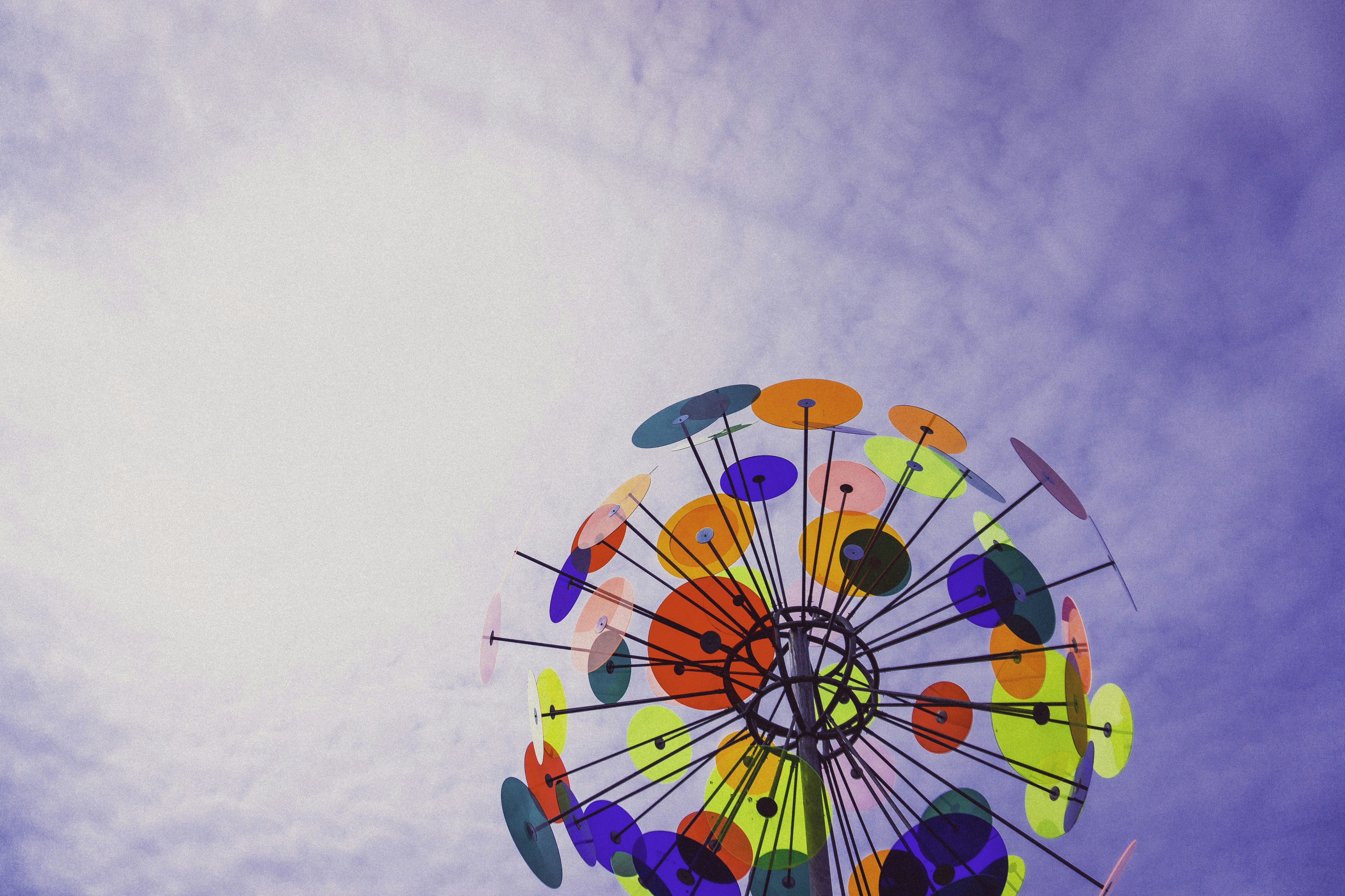 a colorful ferris wheel in the middle of a cloudy sky