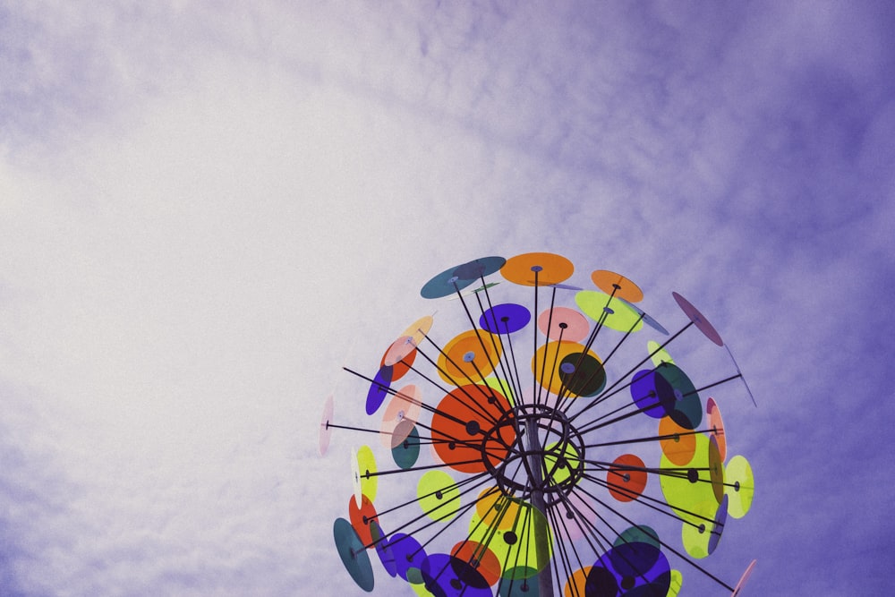 a colorful ferris wheel in the middle of a cloudy sky