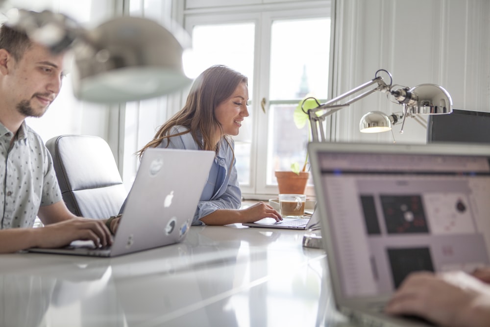 a couple of people sitting at a table with laptops