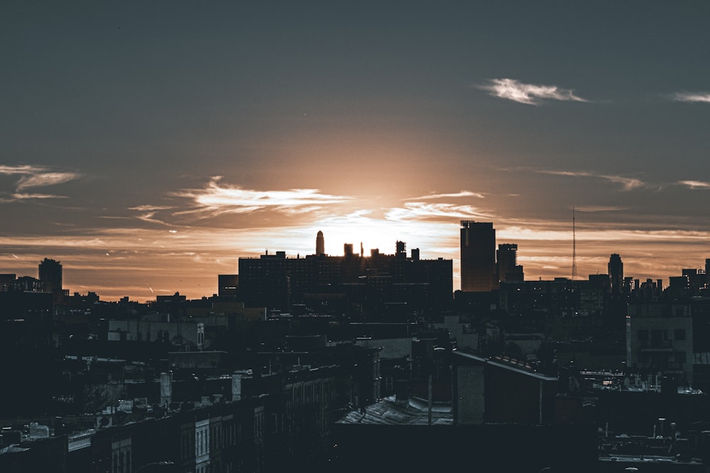 the sun is setting over a city with tall buildings