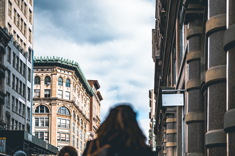 a woman walking down a street next to tall buildings