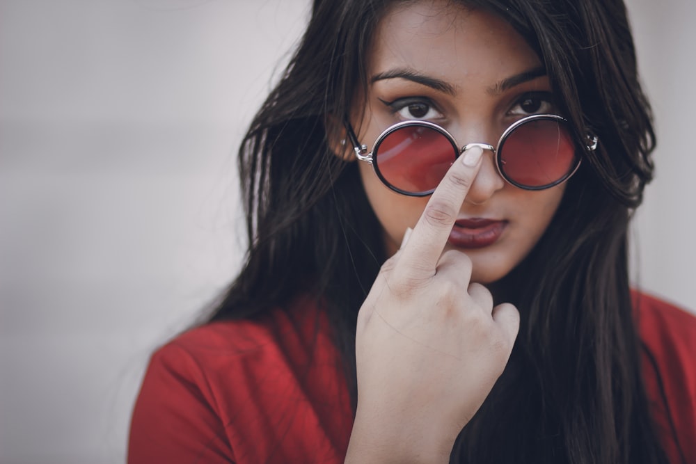 a woman wearing red glasses looking through a pair of round glasses